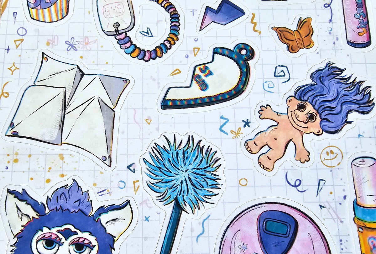 A close-up of colorful sticker decals featuring various whimsical illustrations, including a blue-haired troll character, a blue flower, a white envelope, and other doodle-style graphics, arranged on a light grid background.