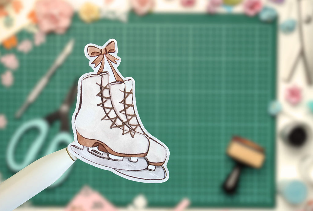 White ice skate with brown details on a green cutting mat with crafting tools.