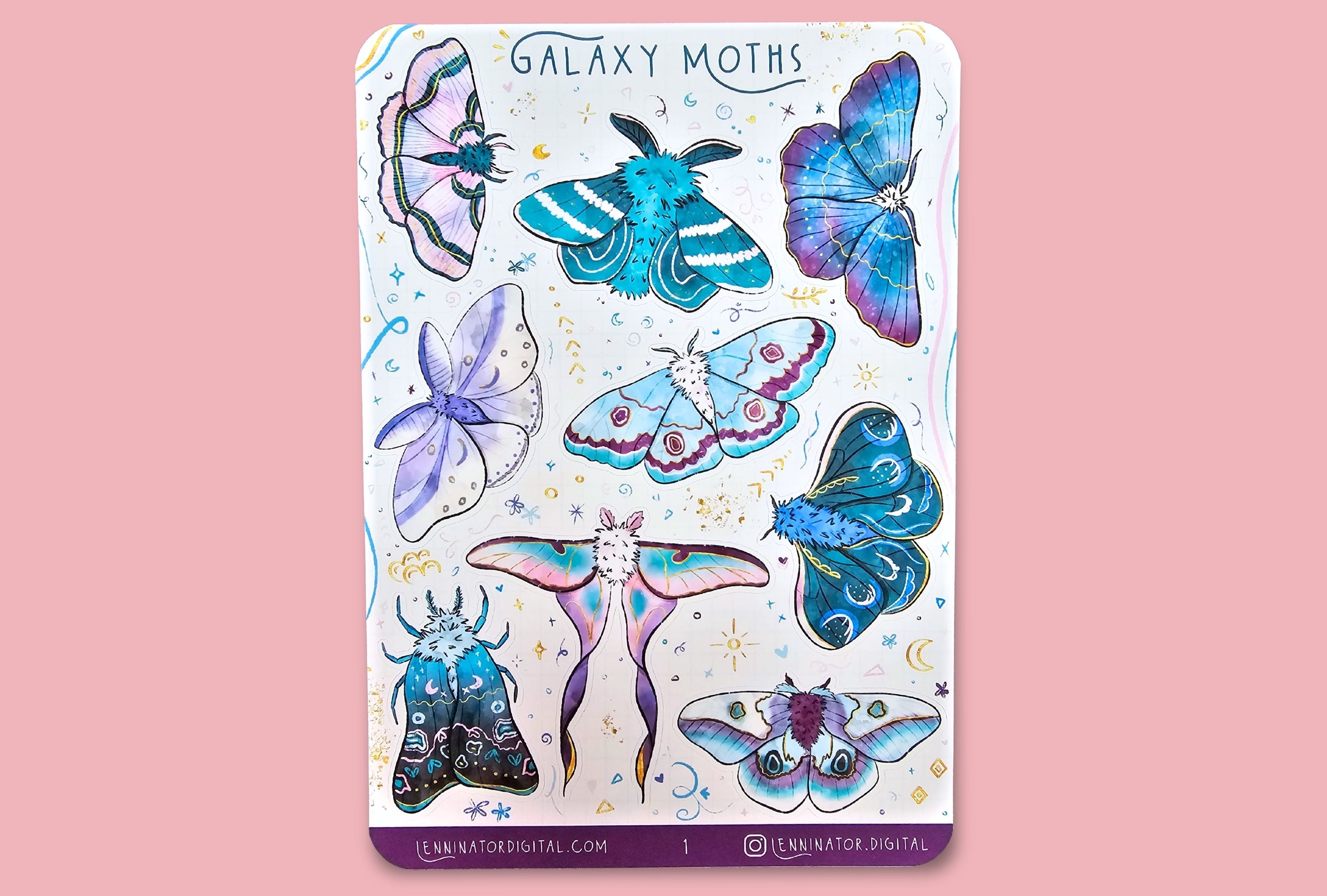 Sticker album with galaxy moth designs on a pink background with stationery items.