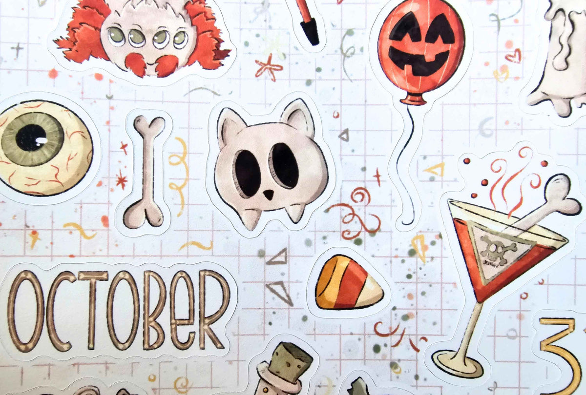 A close-up of a die-cut sticker sheet featuring Halloween and October-themed illustrations, including a jack-o'-lantern balloon, a spooky clown head, a cat face, an eyeball, a bone, candy corn, a martini glass, and the word 'OCTOBER' on a lined paper background.