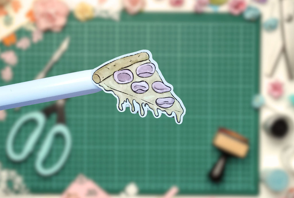 Pizza slice sticker on a pen with a crafting background