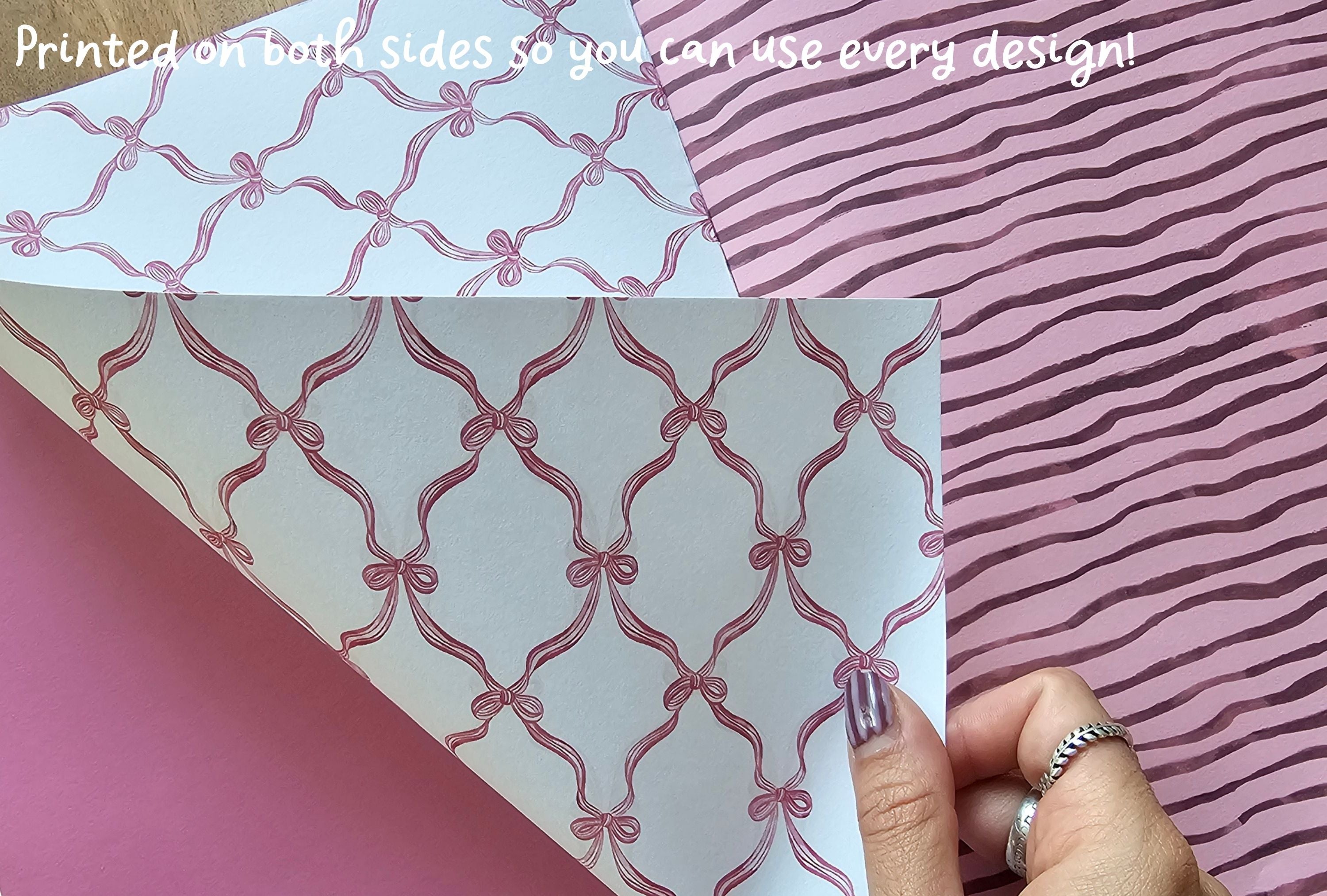 Patterned paper with pink bows on a pink background, held by a hand.