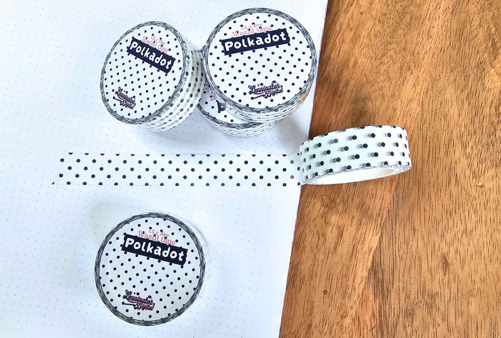 Three rolls of Polkadot brand washi tape with a black and white polka dot pattern, displayed on a white dotted paper next to a wooden surface.