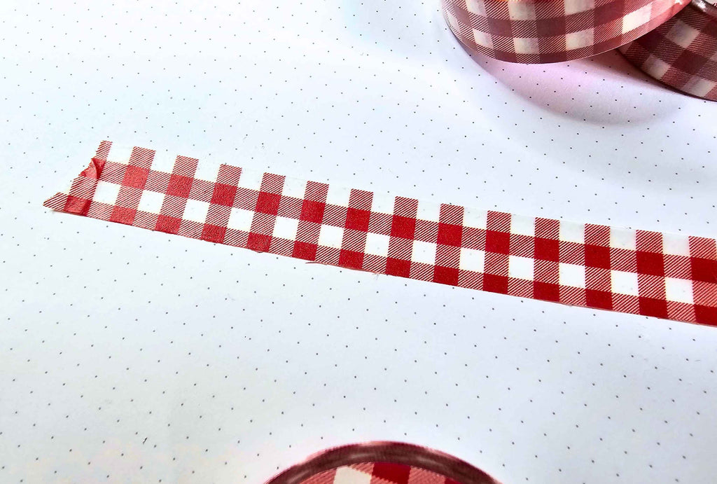 a close up of a washi tape stuck on paper with red and white gingham pattern,