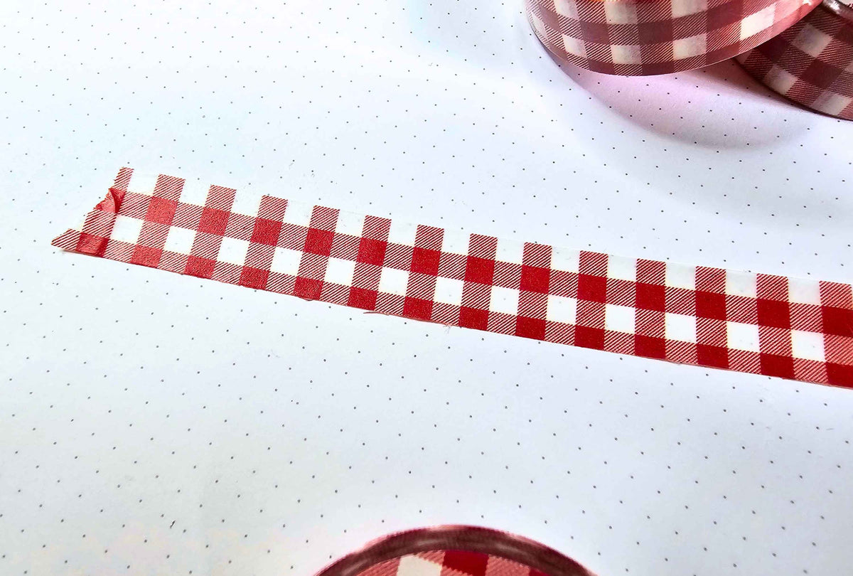 a close up of a washi tape stuck on paper with red and white gingham pattern,