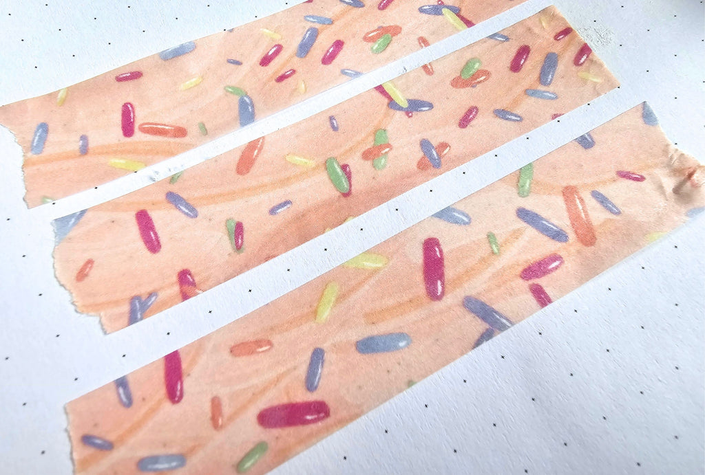 Three strips of washi tape paper with colorful candy-like sprinkles on a white background