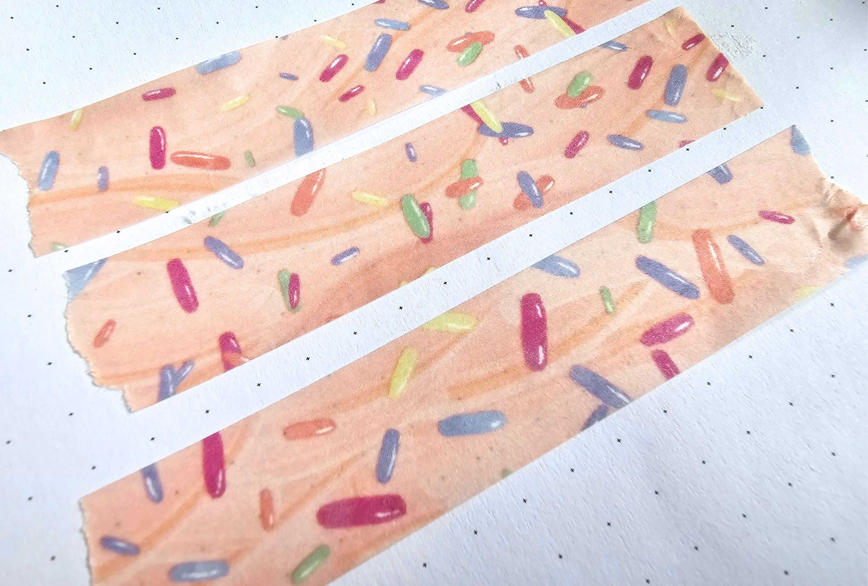 Three strips of washi tape paper with colorful candy-like sprinkles on a white background