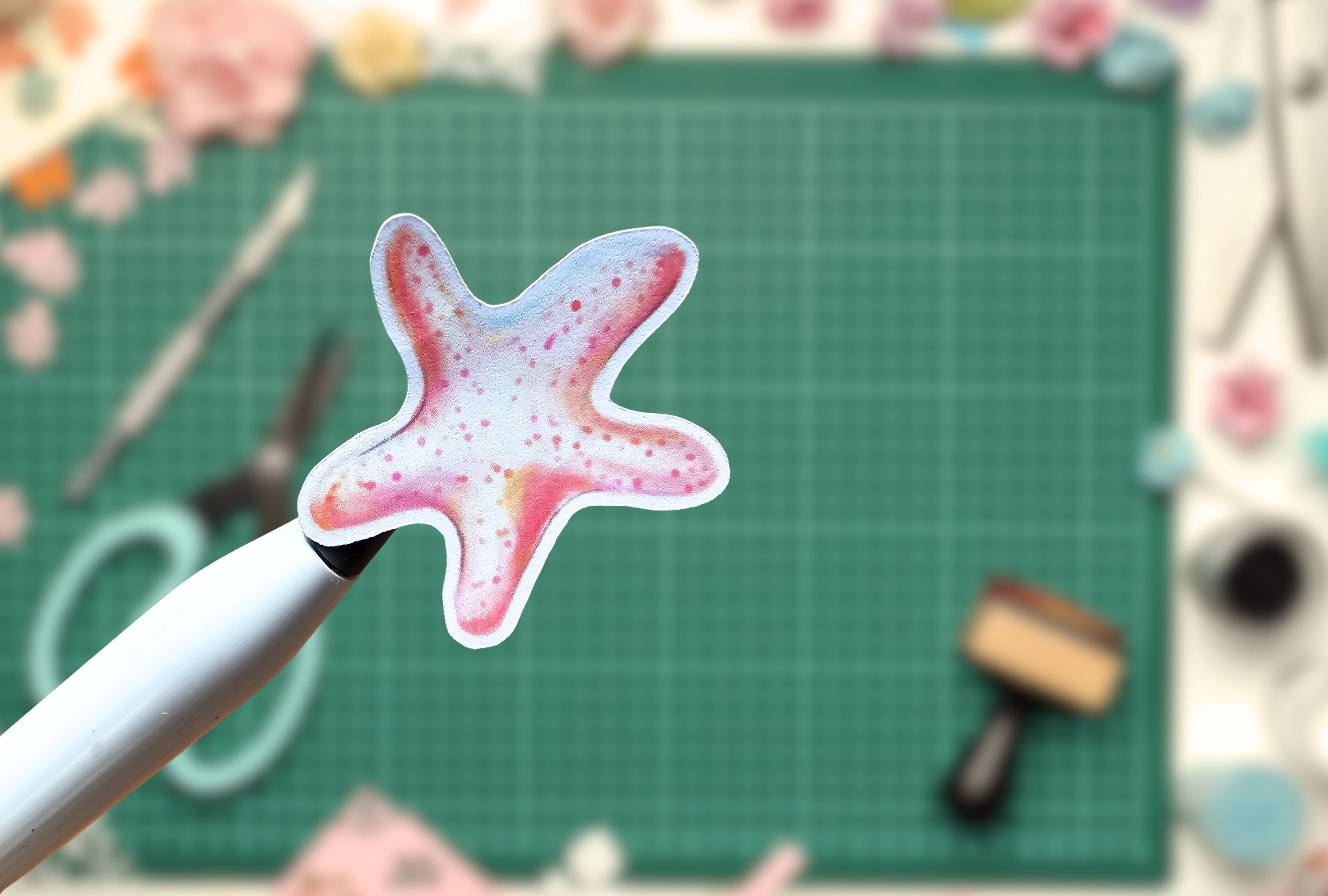 pink starfish on a pen with a green cutting mat and crafting tools in the background