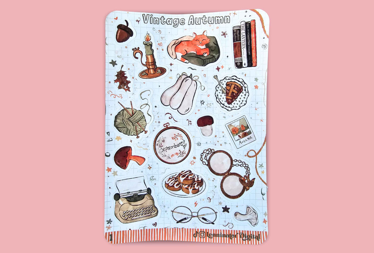 A sticker sheet with a light blue grid background, featuring a 'Vintage Autumn' themed collage of illustrations including a cat, books, a typewriter, glasses, and autumn motifs. The sticker sheet is displayed flat against a solid pink background.